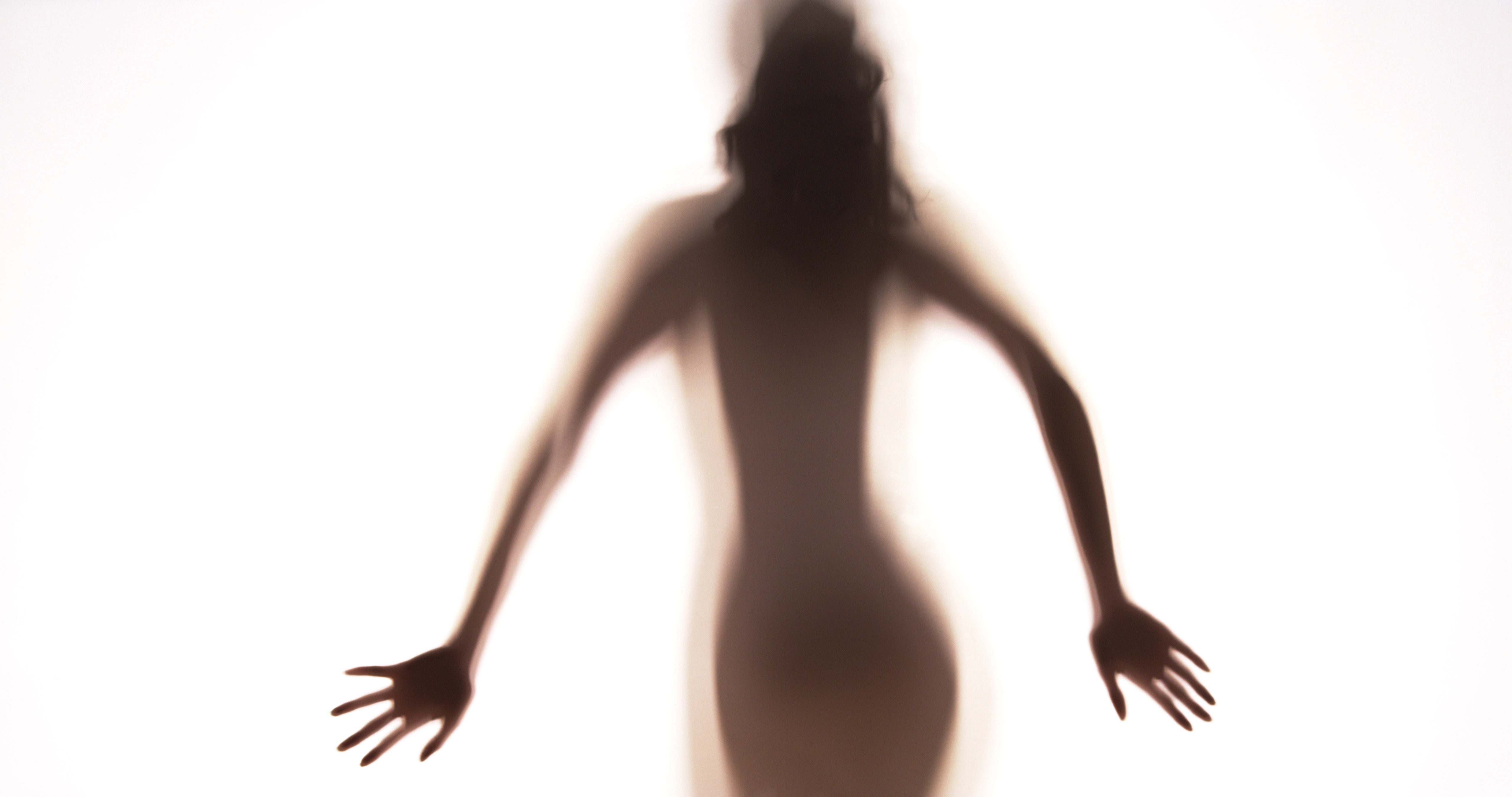 Backlit silhouette of a figure with arms open